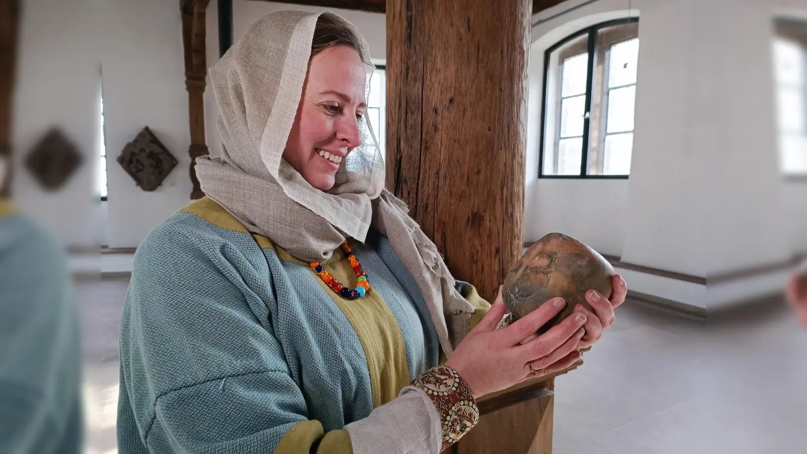 Eine Sächsin (Reenactment Darstellerin Sally Schönnekess) gekleidet wie im 8. Jahrhundert hält ein Webgewicht, das mit einem Kreuz verziert ist. Archäologen haben es in Höxter gefunden – diese Zeugnis aus dem frühchristlichen Höxter wird ab dem 10. Mai gezeigt in der Ausstellung „Die Schlacht am Brunsberg – Aufbruch in eine neue Zeit“. (Foto: Huxarium Gartenpark Höxter/Manuela Puls)