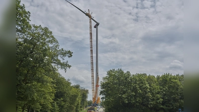 Präzisionsarbeit in schwindelerregender Höhe: Das erste der jeweils rund 25 Tonnen und 78 Meter langen Rotorblätter konnte jetzt an der ersten Anlage auf dem Bratberg montiert werden. Wie riesig die Anlage ist, lässt sich im Vergleich der am Fuße abgestellten Fahrzeuge erkennen. (Foto: Stefan Bönning)