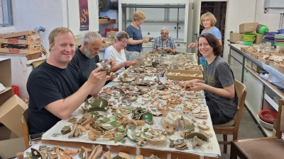 Christian Baie, Jürgen Krug, Margrit Hofmeister, Eva Zahradnicek, Dr. Christian Leiber, Elvira Mill und Lena Hilmer bei Bearbeitung der archäologischen Funde in der Werkstatt im Schloss Bevern . (Foto: Landkreis Holzminden)