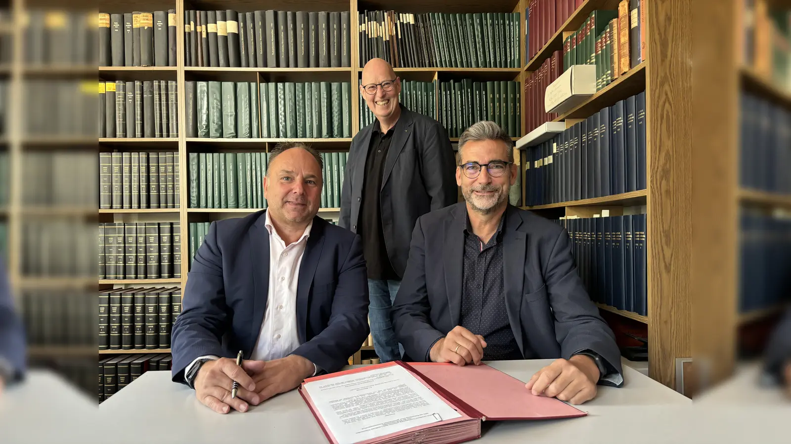 Unterschrift im Kreisarchiv für die gemeinsame Bewahrung historischen Erbes: Landrat Michael Schünemann und Bürgermeister Christian Belke zusammen mit Dr. Hilko Linnemann im Kreisarchiv, das mit dem Stadtarchiv verschmilzt. (Foto: Peter Drews/Landkreis Holzminden)