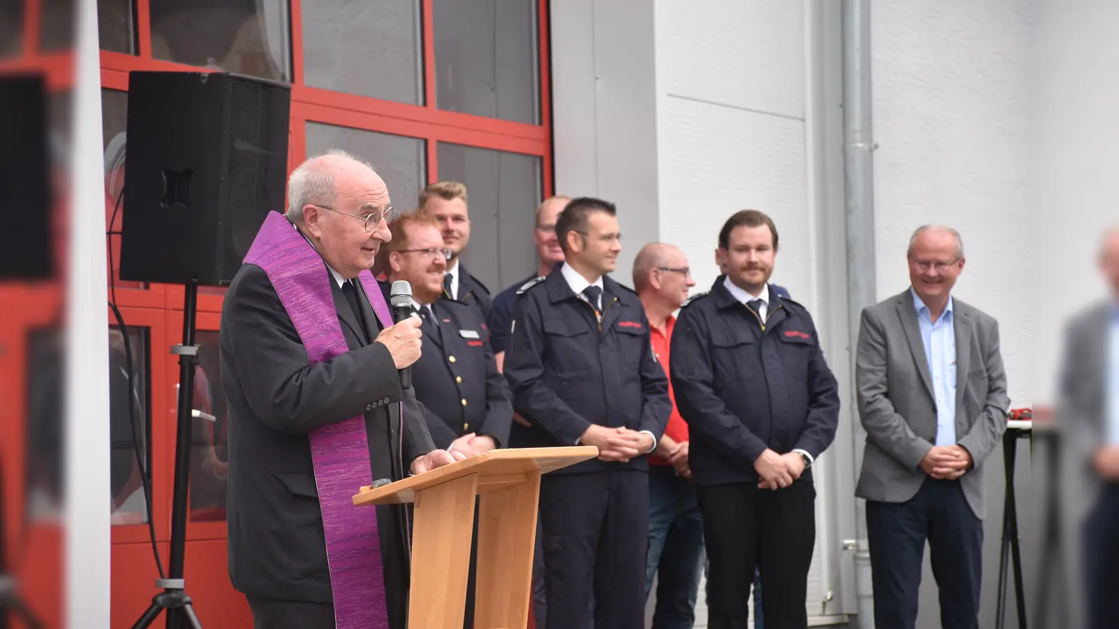 Mit Andacht und Weihwasser gab Pastor Günter Weige dem neuen Fahrzeug und dem Anbau den Segen und bat um göttlichen Schutz für die ehrenamtlichen Feuerwehrleute. (Im Hintergrund v. l.) Kreisbrandmeister Stefan Nostitz, der Leiter der FFW Beverungen Sebastian Even, Löschgruppenführer Nils Hanewinkel und Bürgermeister Hubertus Grimm. (Foto: Barbara Siebrecht)